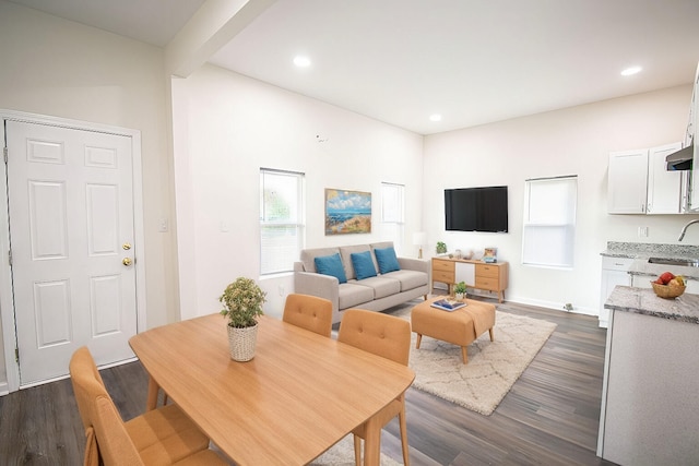 dining space with dark wood-type flooring, sink, and beamed ceiling