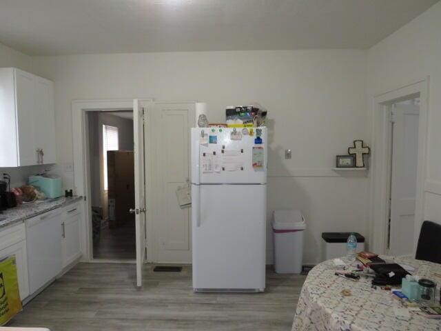 kitchen with white cabinetry, white appliances, light hardwood / wood-style flooring, and light stone countertops