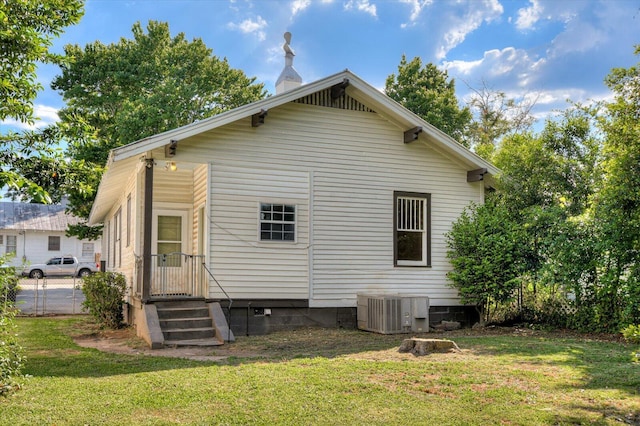 rear view of property featuring a yard and central AC unit