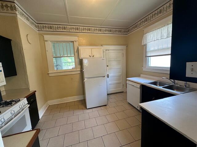 kitchen featuring light tile patterned floors, white appliances, white cabinetry, and sink