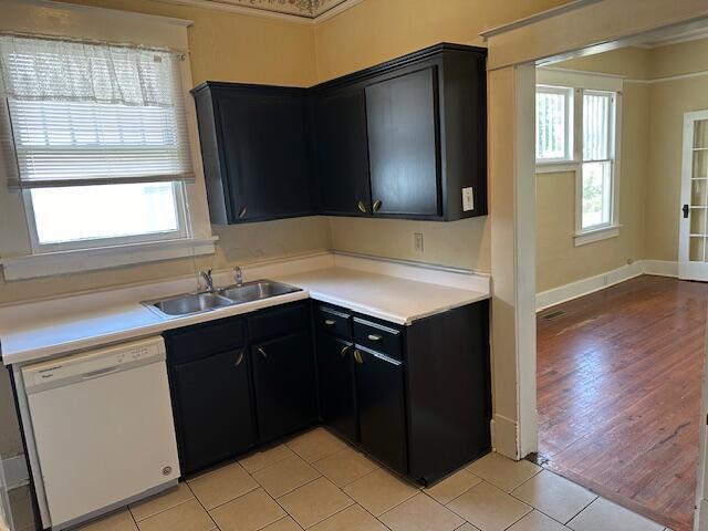 kitchen with light tile patterned floors, white dishwasher, a wealth of natural light, and sink