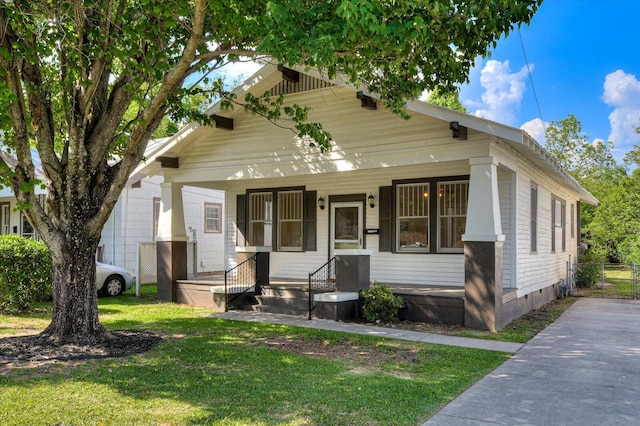 bungalow featuring covered porch and a front yard