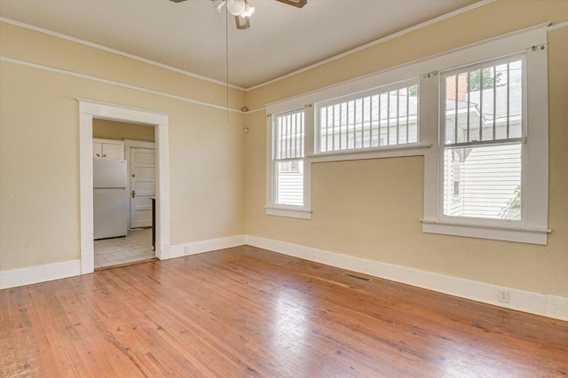 empty room with ceiling fan, wood-type flooring, and crown molding