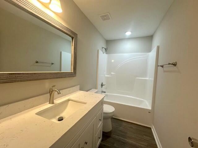 full bathroom with vanity, hardwood / wood-style flooring, shower / bathing tub combination, and toilet