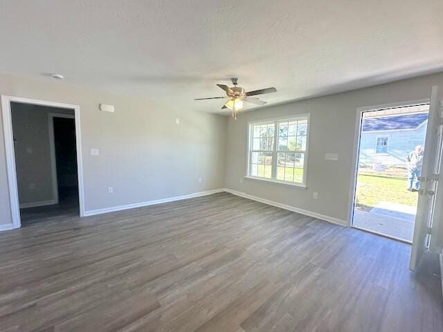 empty room with ceiling fan and dark hardwood / wood-style flooring