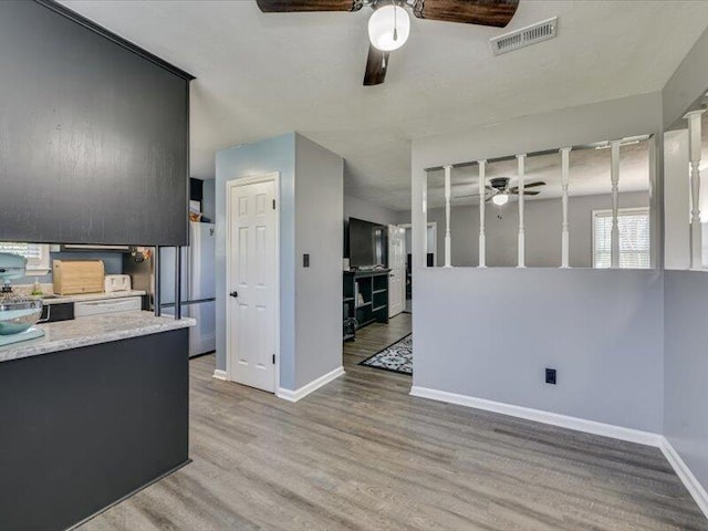 kitchen with visible vents, ceiling fan, light countertops, freestanding refrigerator, and wood finished floors