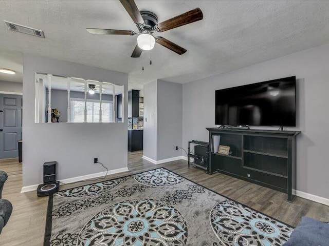 living area with visible vents, a textured ceiling, and wood finished floors