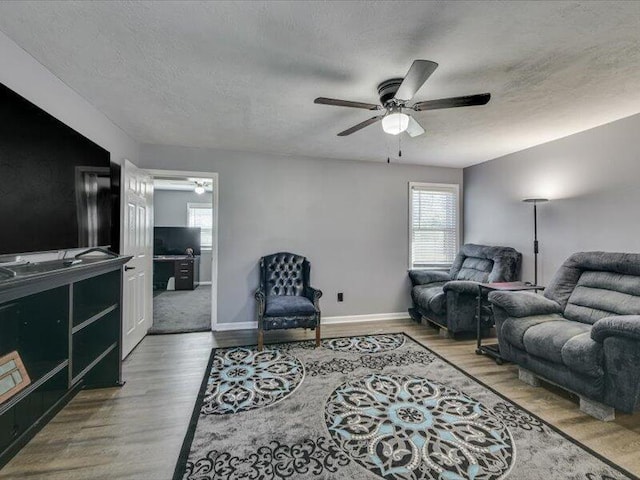 living area featuring a textured ceiling, wood finished floors, and ceiling fan