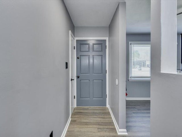 doorway featuring baseboards and wood finished floors