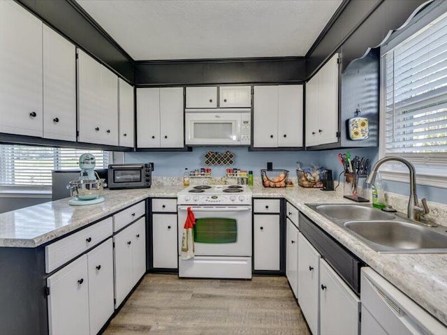 kitchen with white appliances, white cabinets, light countertops, and a sink