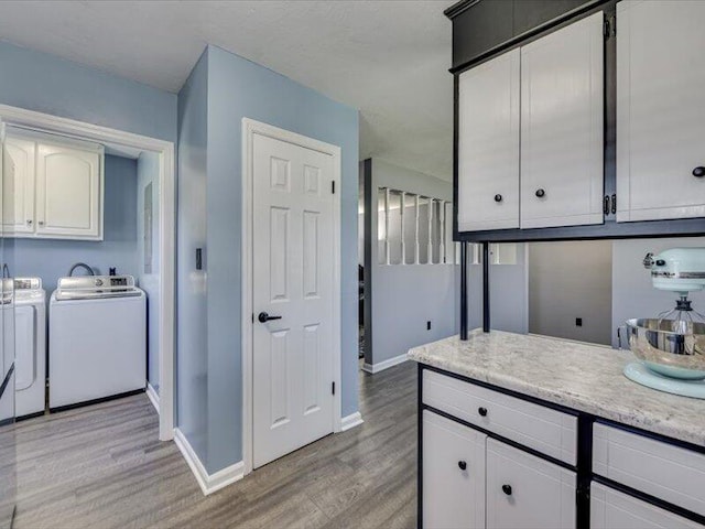 kitchen with baseboards, washing machine and dryer, light countertops, light wood-style flooring, and white cabinets