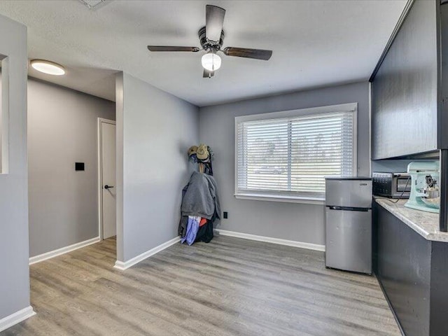 unfurnished office featuring light wood-style flooring, a toaster, baseboards, and ceiling fan