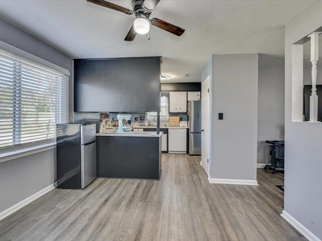 kitchen with light wood-type flooring, dishwasher, light countertops, and freestanding refrigerator