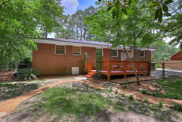 rear view of house with fence, a wooden deck, brick siding, a gate, and crawl space