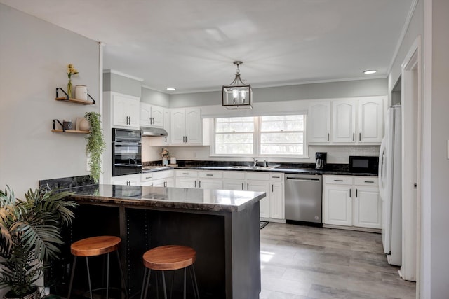 kitchen featuring black appliances, a sink, a peninsula, crown molding, and a kitchen breakfast bar