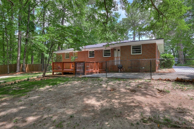 back of house with fence, brick siding, and a deck