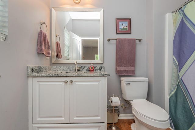 full bath featuring vanity, baseboards, wood finished floors, and toilet