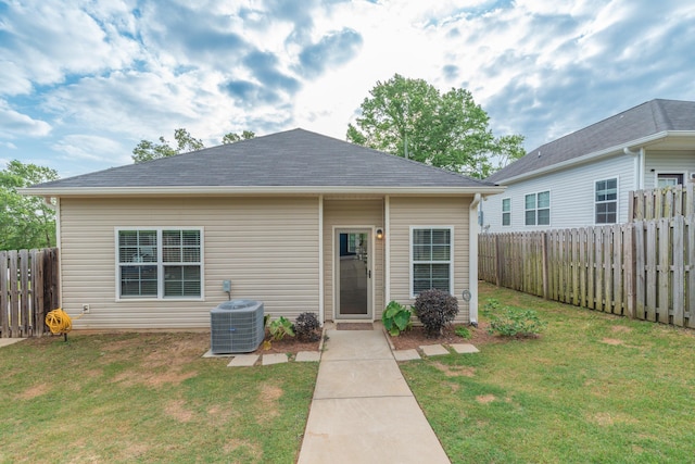 view of front of property with a fenced backyard, a front lawn, and cooling unit