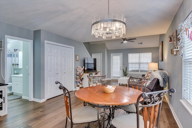 dining space featuring a textured ceiling, light wood-type flooring, visible vents, and baseboards