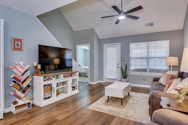 living room featuring baseboards, visible vents, a ceiling fan, lofted ceiling, and wood finished floors