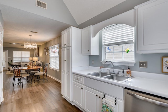 kitchen with visible vents, stainless steel dishwasher, white cabinets, vaulted ceiling, and a sink