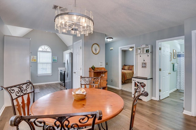 dining area featuring lofted ceiling, visible vents, a textured ceiling, and wood finished floors