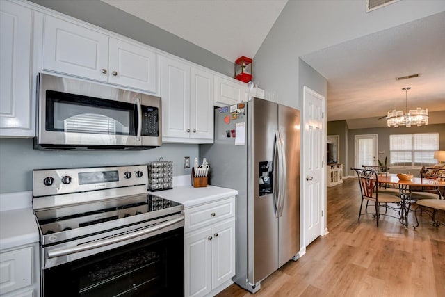 kitchen with lofted ceiling, light countertops, appliances with stainless steel finishes, light wood-style floors, and white cabinets