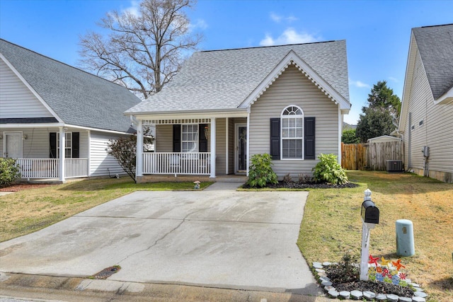 view of front of house featuring a porch, a shingled roof, central AC, fence, and a front lawn