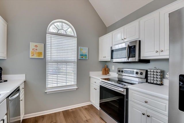 kitchen with appliances with stainless steel finishes, lofted ceiling, white cabinets, and light countertops