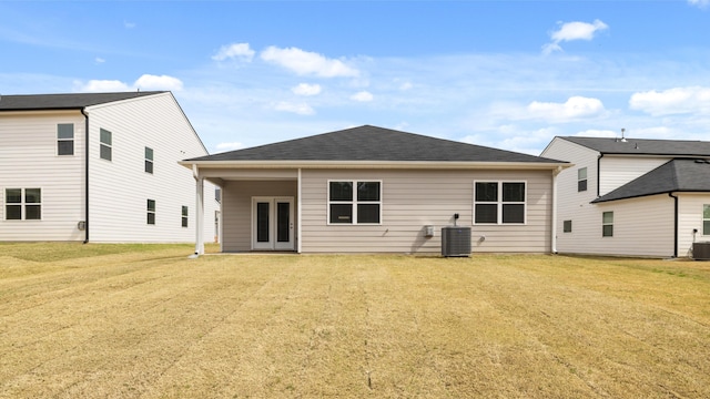 back of house featuring cooling unit, french doors, a lawn, and roof with shingles