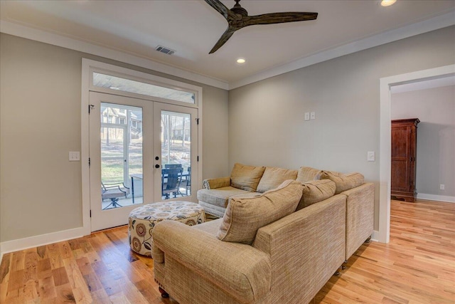 living room featuring crown molding, light wood-type flooring, ceiling fan, and french doors