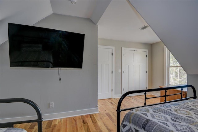 bedroom featuring light hardwood / wood-style flooring and lofted ceiling