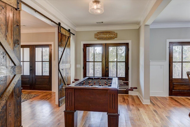 playroom featuring french doors, a barn door, ornamental molding, and plenty of natural light