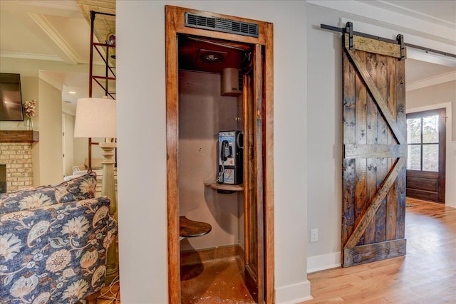 corridor with hardwood / wood-style flooring, a barn door, and crown molding