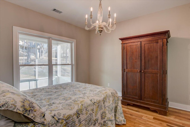 bedroom with light hardwood / wood-style floors and an inviting chandelier