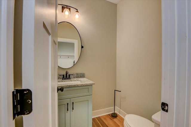 bathroom with hardwood / wood-style floors, toilet, and vanity