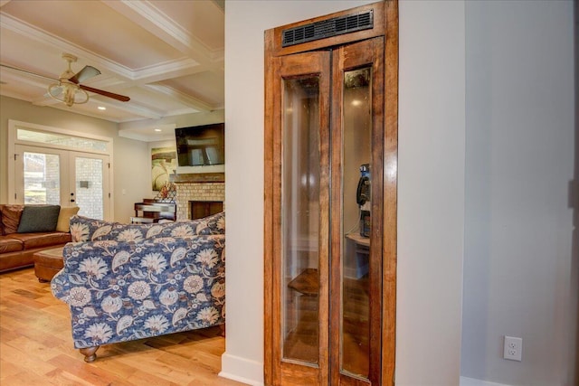 interior space with beamed ceiling, crown molding, light hardwood / wood-style floors, coffered ceiling, and french doors