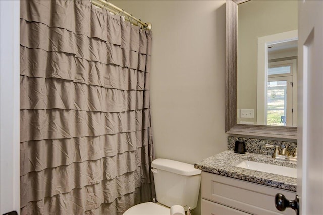 bathroom featuring toilet, vanity, and walk in shower