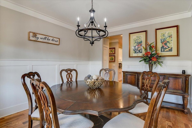 dining area with crown molding, hardwood / wood-style flooring, and an inviting chandelier