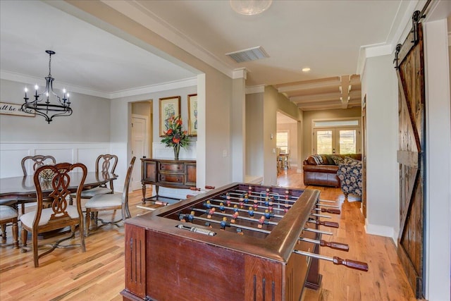 rec room featuring crown molding, light hardwood / wood-style floors, french doors, and a barn door