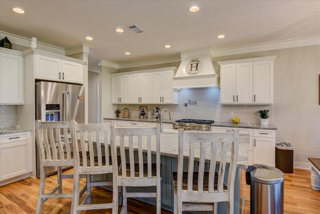 kitchen with white cabinets, stainless steel appliances, and custom range hood