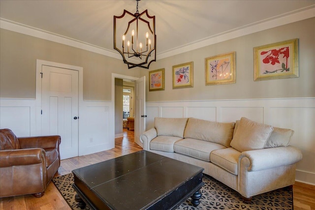 living room featuring wood-type flooring, crown molding, and an inviting chandelier