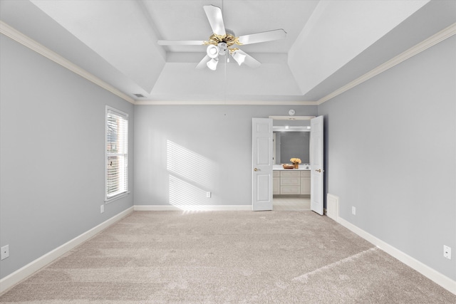 spare room with vaulted ceiling, ceiling fan, a tray ceiling, crown molding, and light carpet