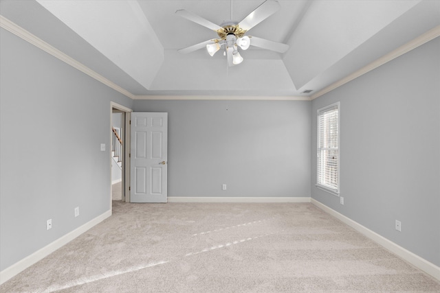 carpeted spare room with crown molding, ceiling fan, and a raised ceiling