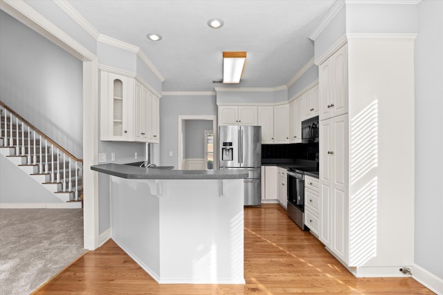 kitchen with white cabinetry, a breakfast bar area, kitchen peninsula, and appliances with stainless steel finishes