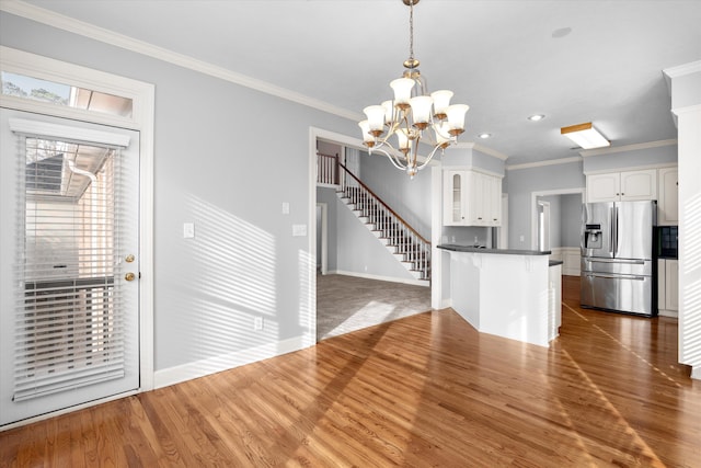 kitchen with dark wood-type flooring, hanging light fixtures, ornamental molding, white cabinets, and stainless steel fridge with ice dispenser