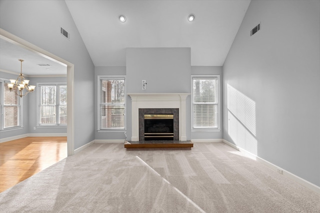 unfurnished living room featuring light carpet, a notable chandelier, and high vaulted ceiling