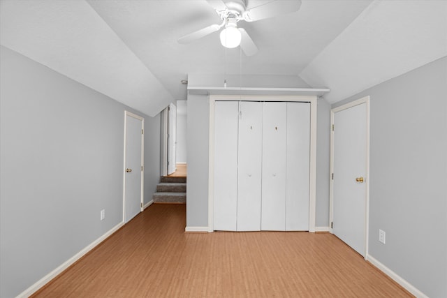 unfurnished bedroom with hardwood / wood-style floors, vaulted ceiling, a closet, and ceiling fan