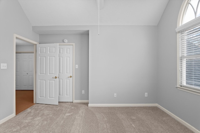 unfurnished bedroom featuring vaulted ceiling and light colored carpet