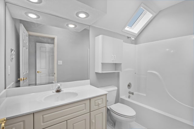 full bathroom with vanity, lofted ceiling with skylight, washtub / shower combination, and toilet